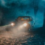 old fashioned car with luminous headlights in dark forest